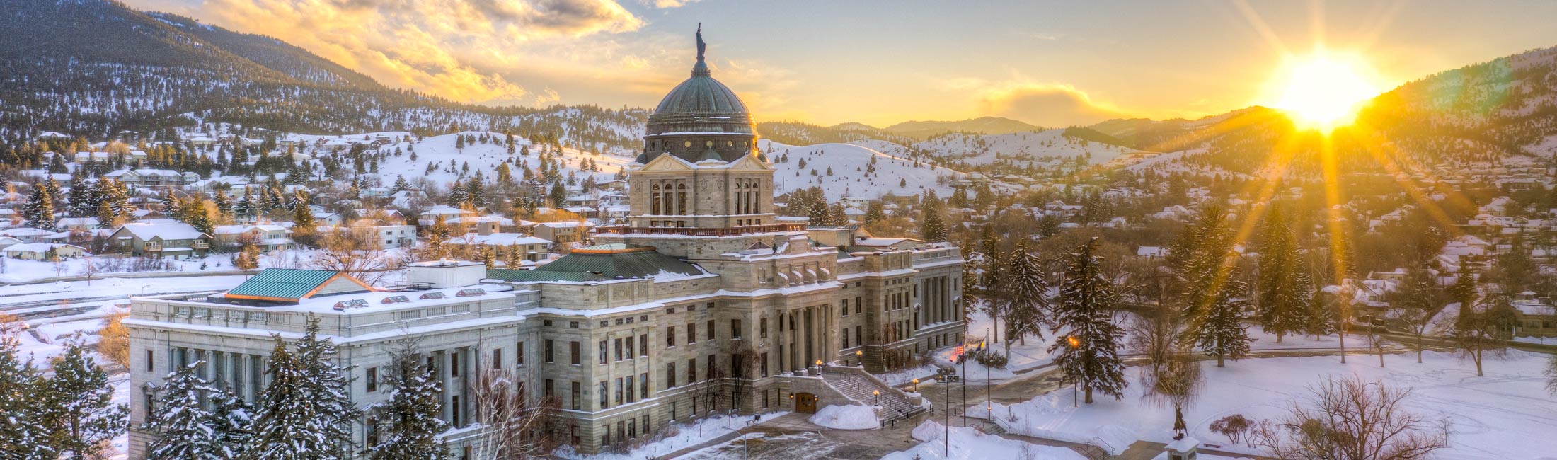 Montana Capitol building in winter with the sun over foothills
