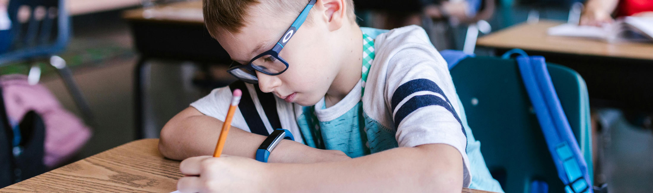 boy writing at school desk