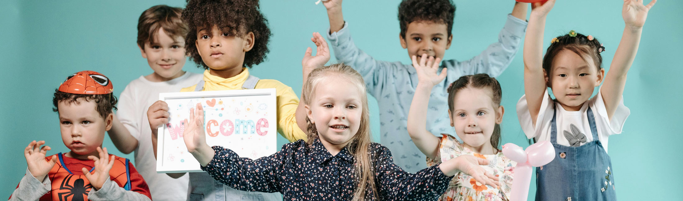 children standing in a group with hands up in the air posing for photo