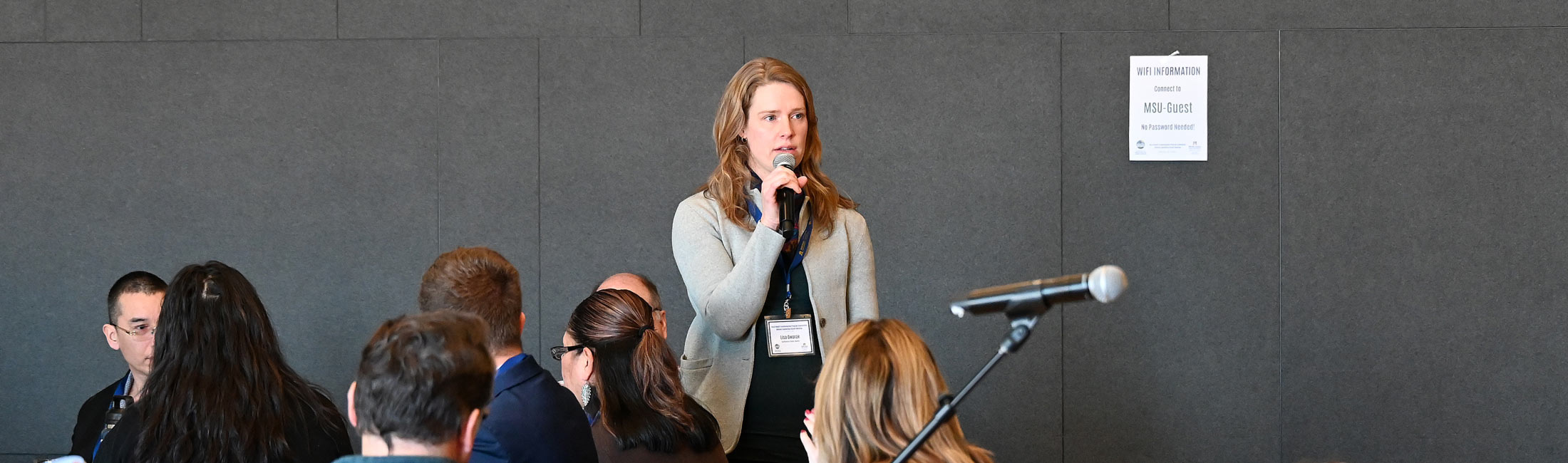 woman standing and speaking into handheld microphone