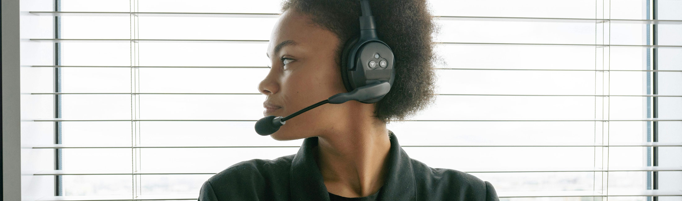 Woman working with a headset on with a microphone piece over her mouth.