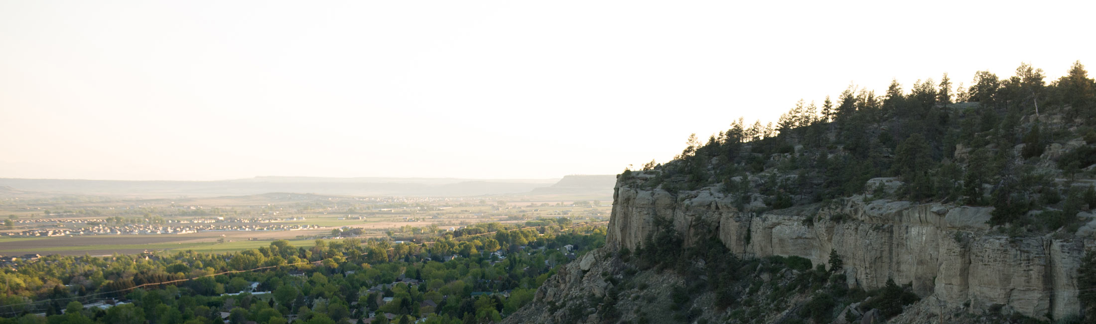rock cliffs with trees and city in background