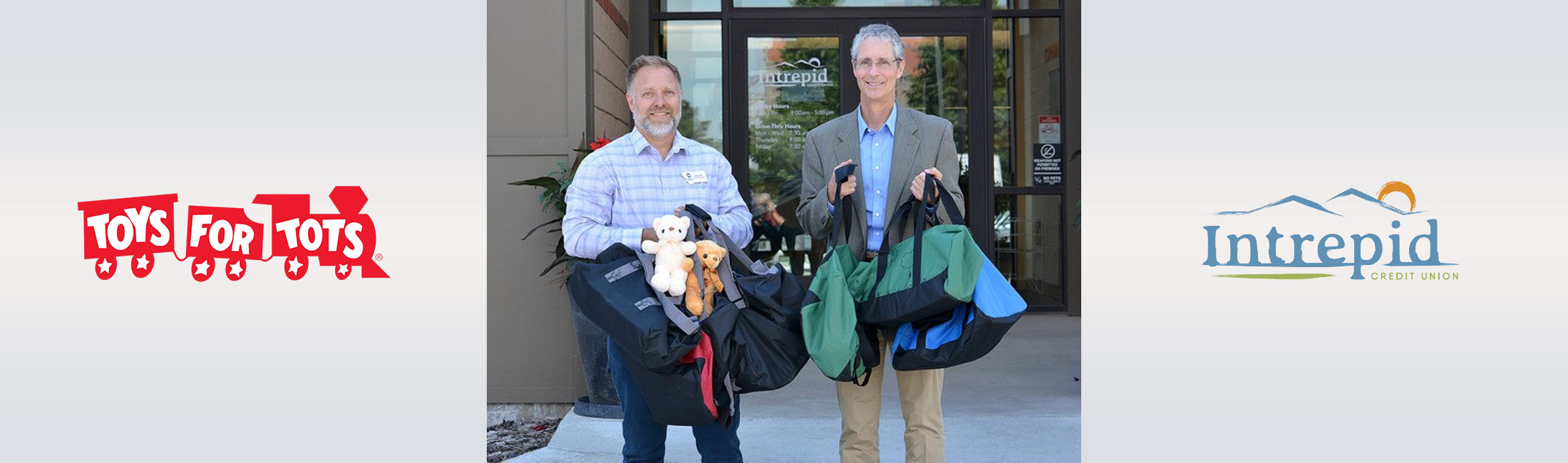 two men standing in from of Intrepid Credit Union holding toys