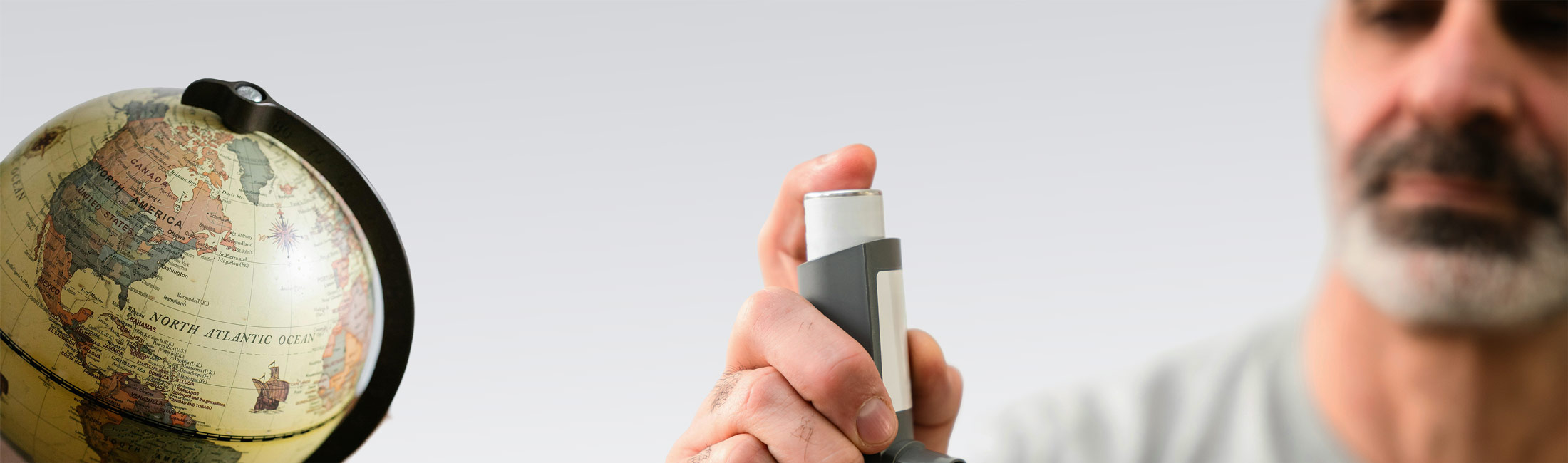 world globe next to man holding inhaler