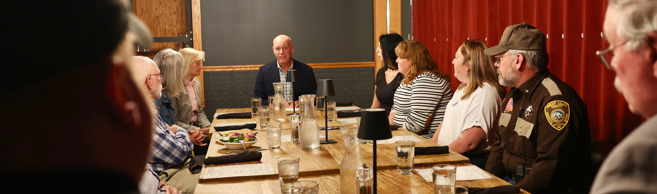 Governor Greg Gianforte seated at table with law enforcement officers, treatment providers, and community members