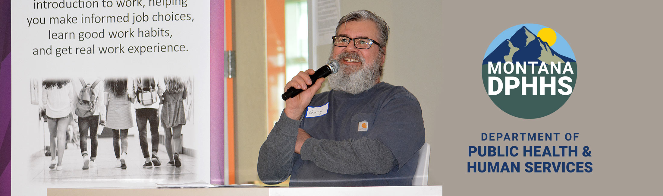 Gary Hicks with microphone speaking while seated at event