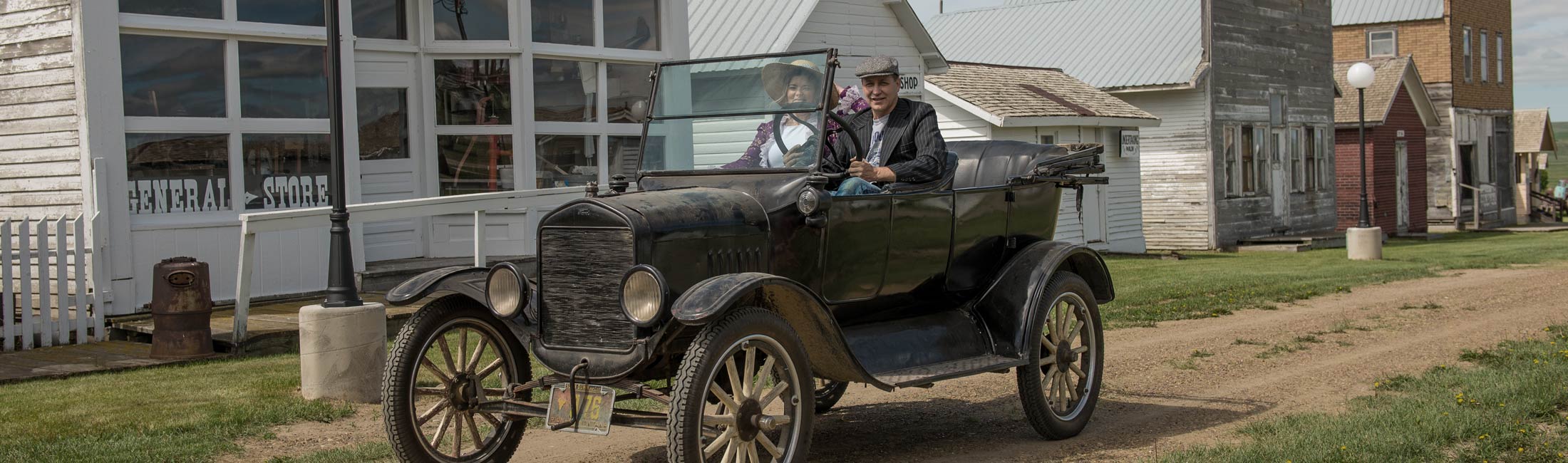 man driving model t car with woman in passenger seat