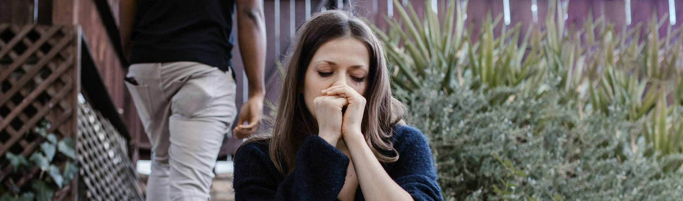 woman sitting with eyes closed with man walking away from her
