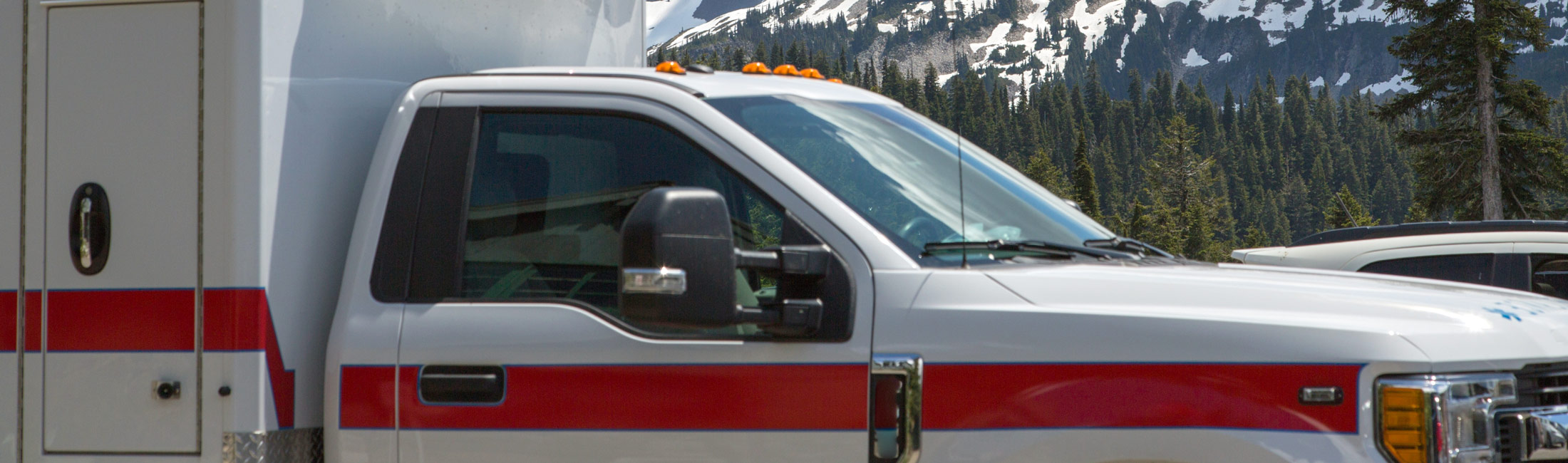 Ambulance in parking lot with snowy mountains in the background