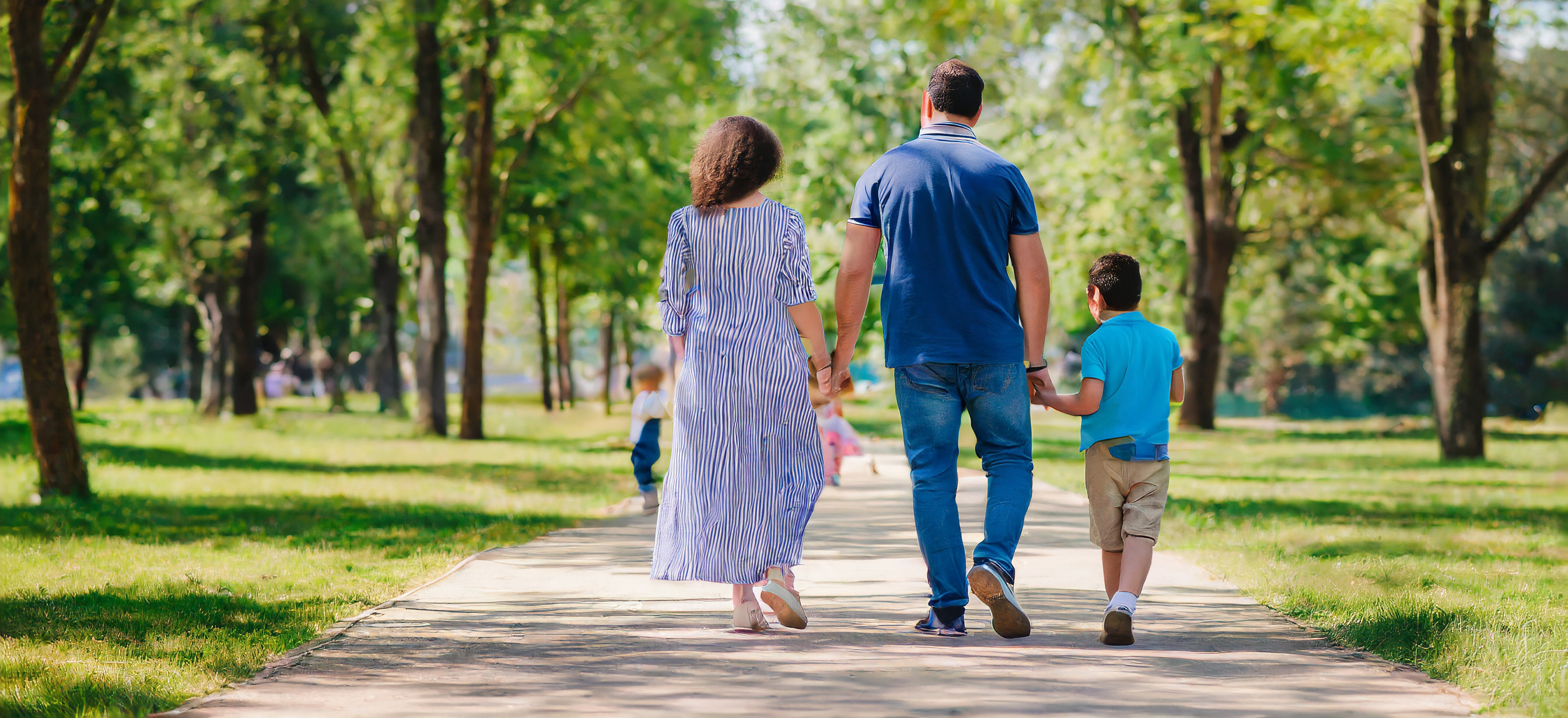 Mother and father with children walking along the path in the park